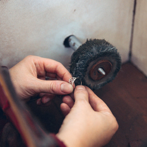 Hands at polishing mop polishing silver ring