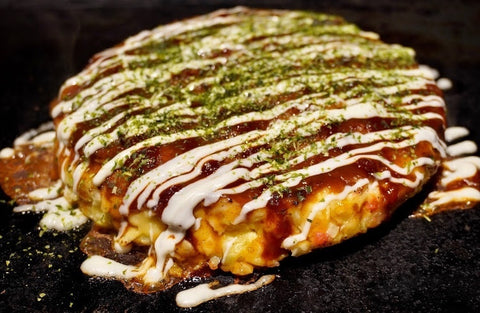 Japanese okonomiyaki savory cabbage pancake on a grill