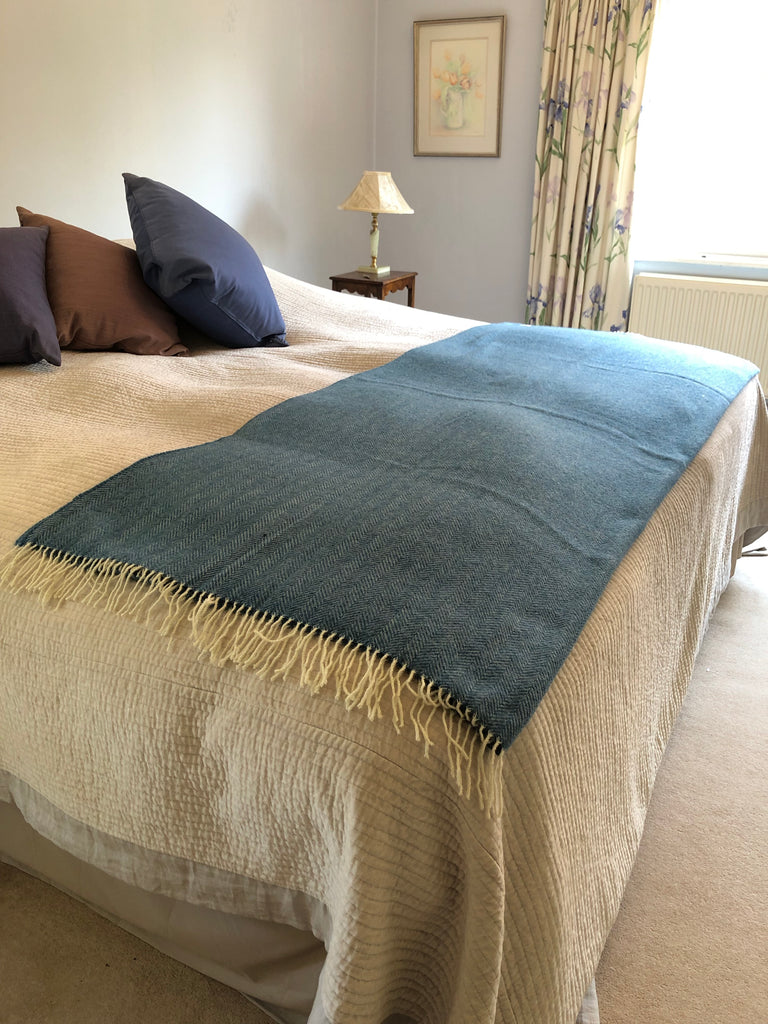 Style idea using a sky blue wool herringbone blanket covering the bottom of a double bed