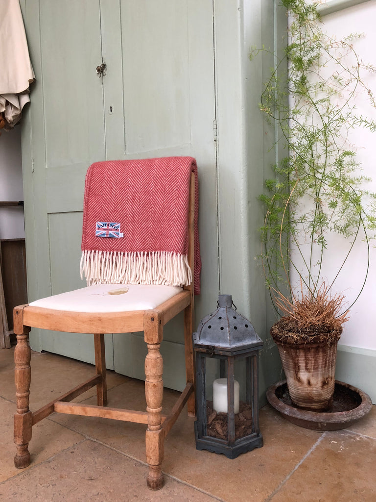 Style idea using a terracotta wool herringbone blanket draped over the back of a wooden chair