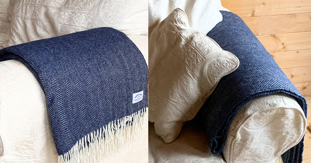 Navy herringbone wool blanket folded over the armrest of a sofa
