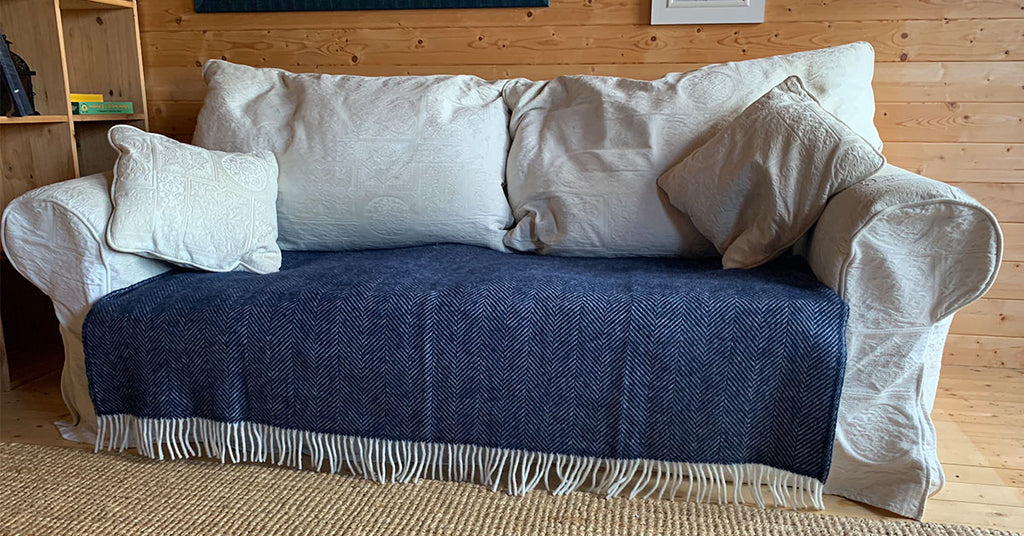 Navy Herringbone Blanket Covering Scuff Marks around the base of a sofa