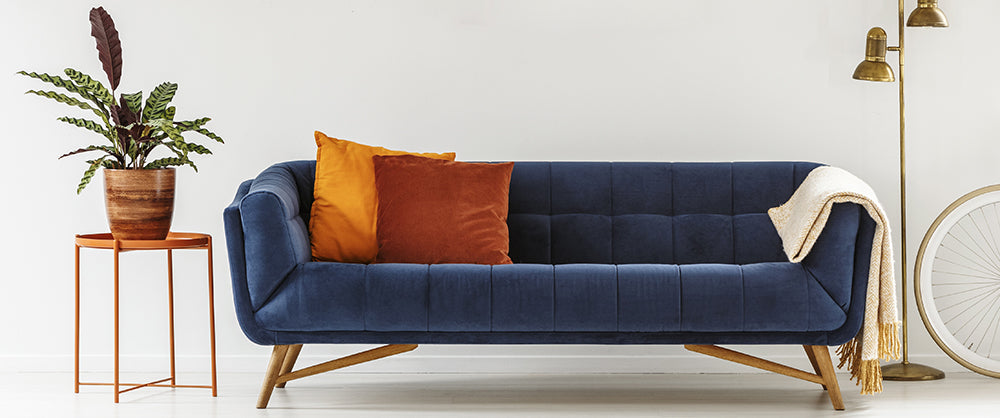 Orange cushions and throws on a blue sofa