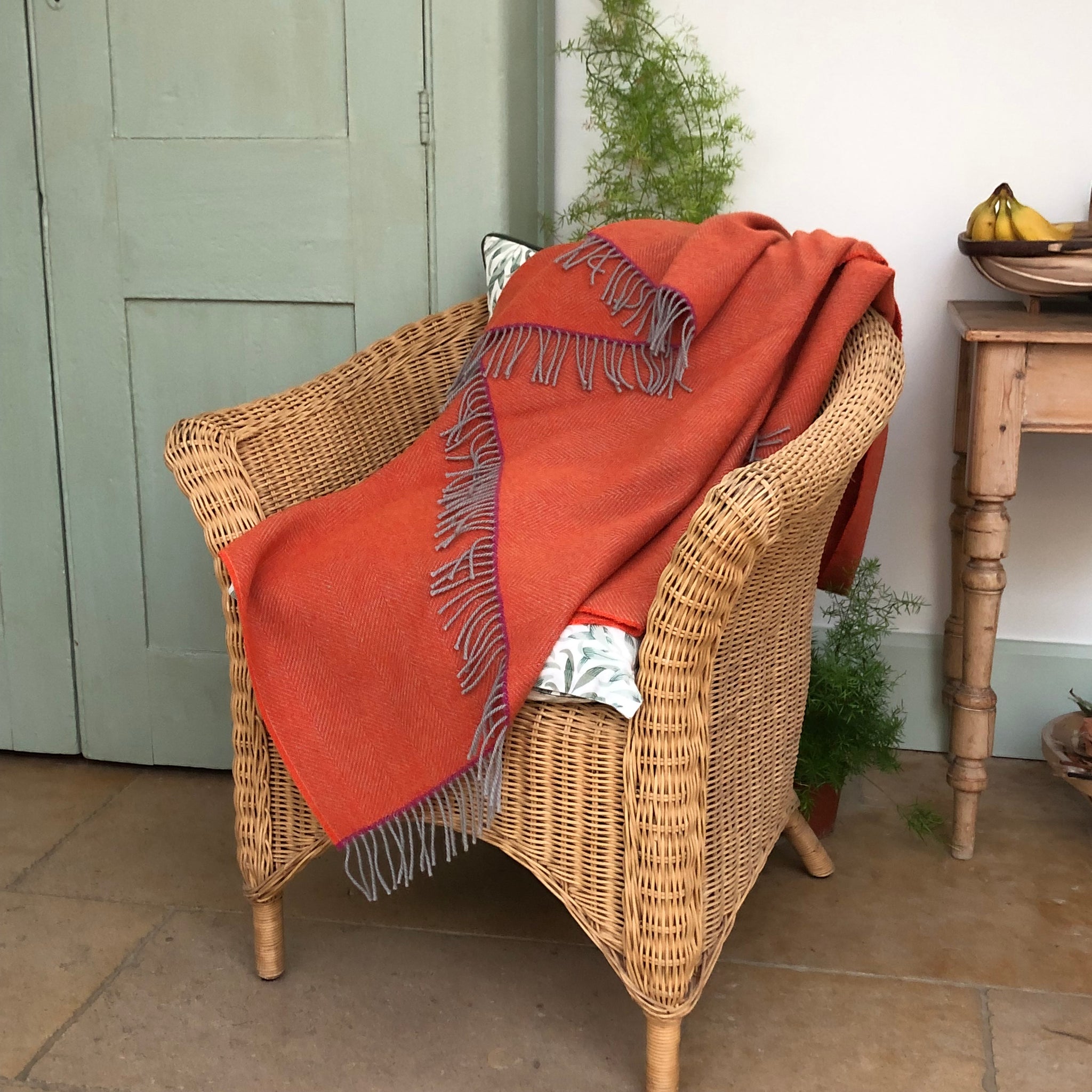 Orange thwo on a wicker chair in a conservatory