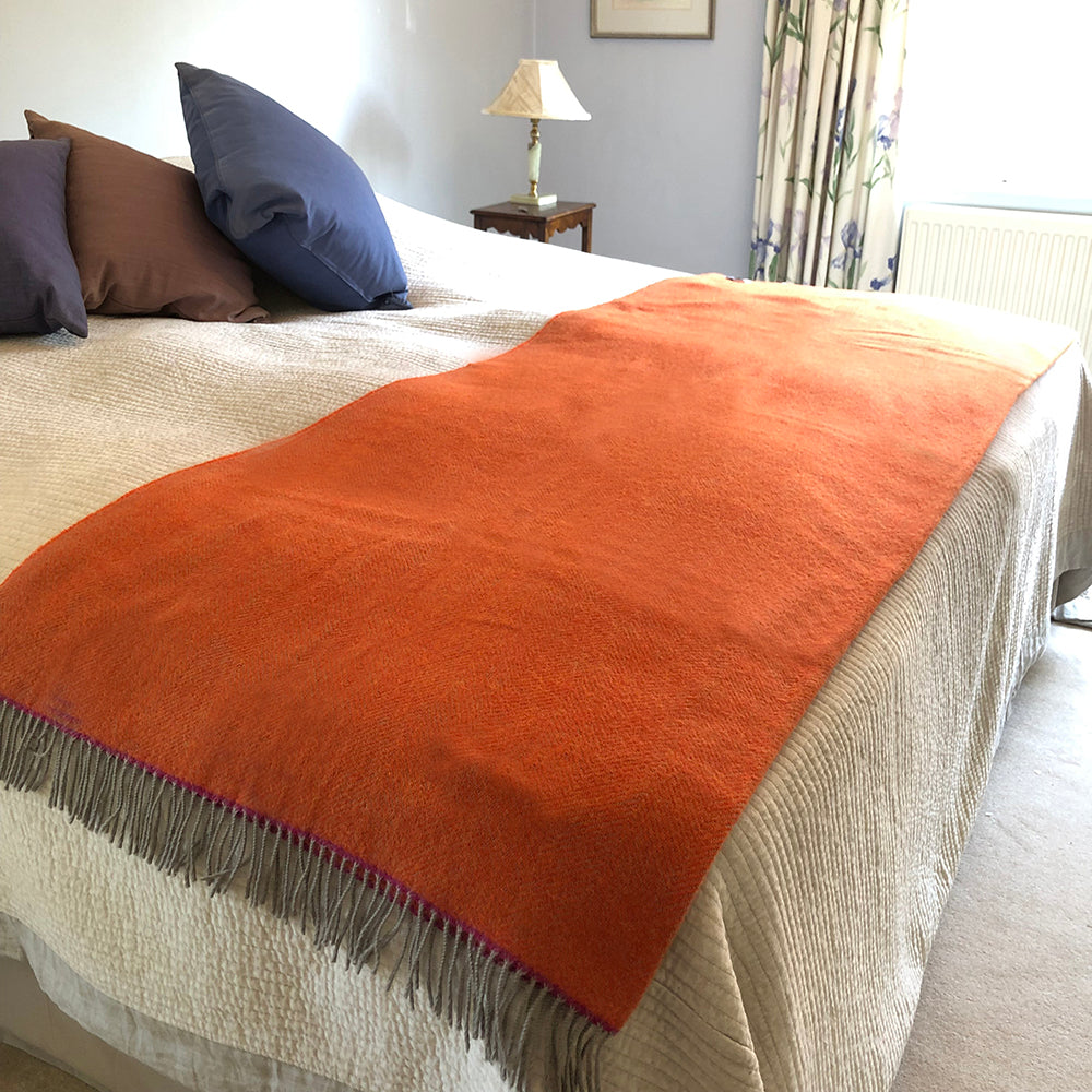 Orange throw at the base of a bed