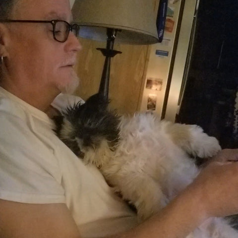 older man cuddling small black and white special needs rescue dog
