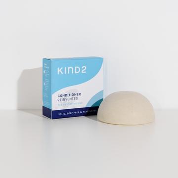 kind2 conidtioner bar in a half sphere shape next to its blue cardboard packaging.