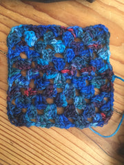 Crocheted granny square in variegated blue yarn