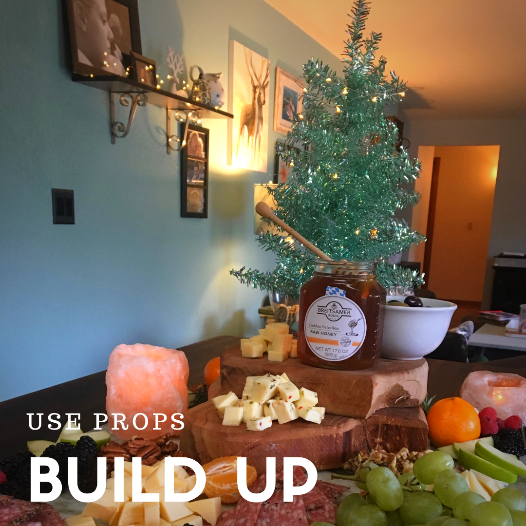 Cheese board with stacked cutting boards and a shiney, mini-Christmas tree.