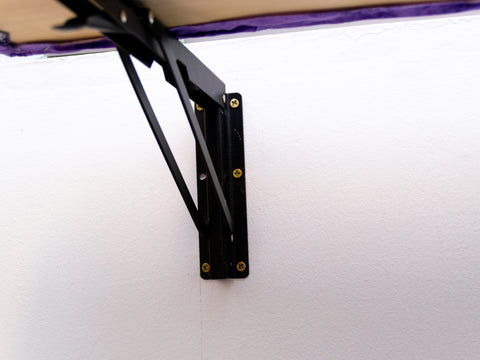 Drop leaf shelf bracket used on a folding ironing board in a small fiber art studio space