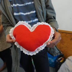 A child holding a red love heart with white ribbon made by hand 