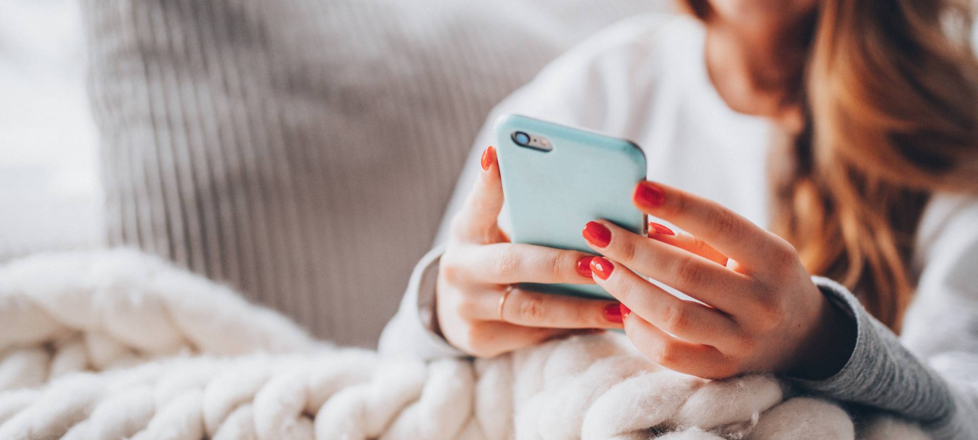 Young woman looking at her phone with a light blue case