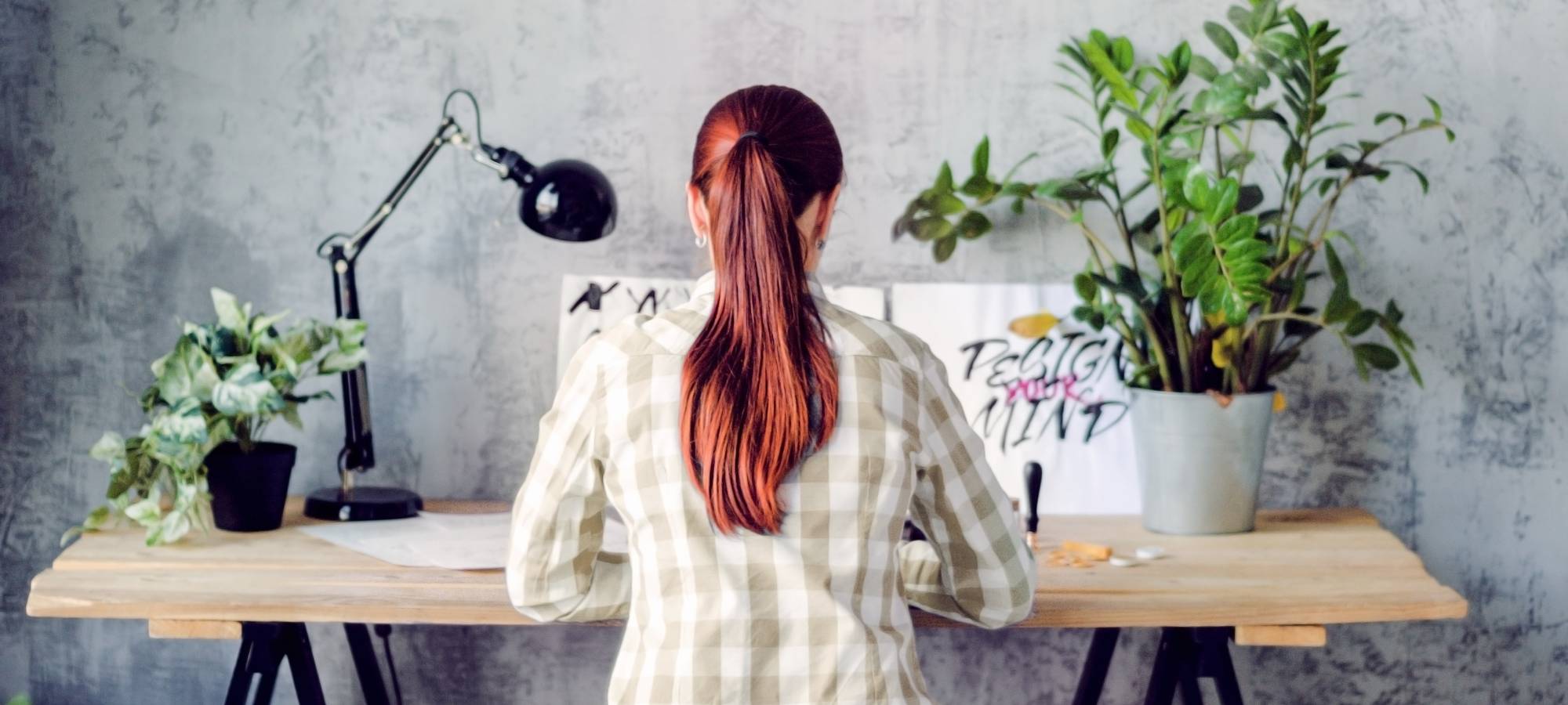 Woman with red hair drawing calligraphy with a desk lamp