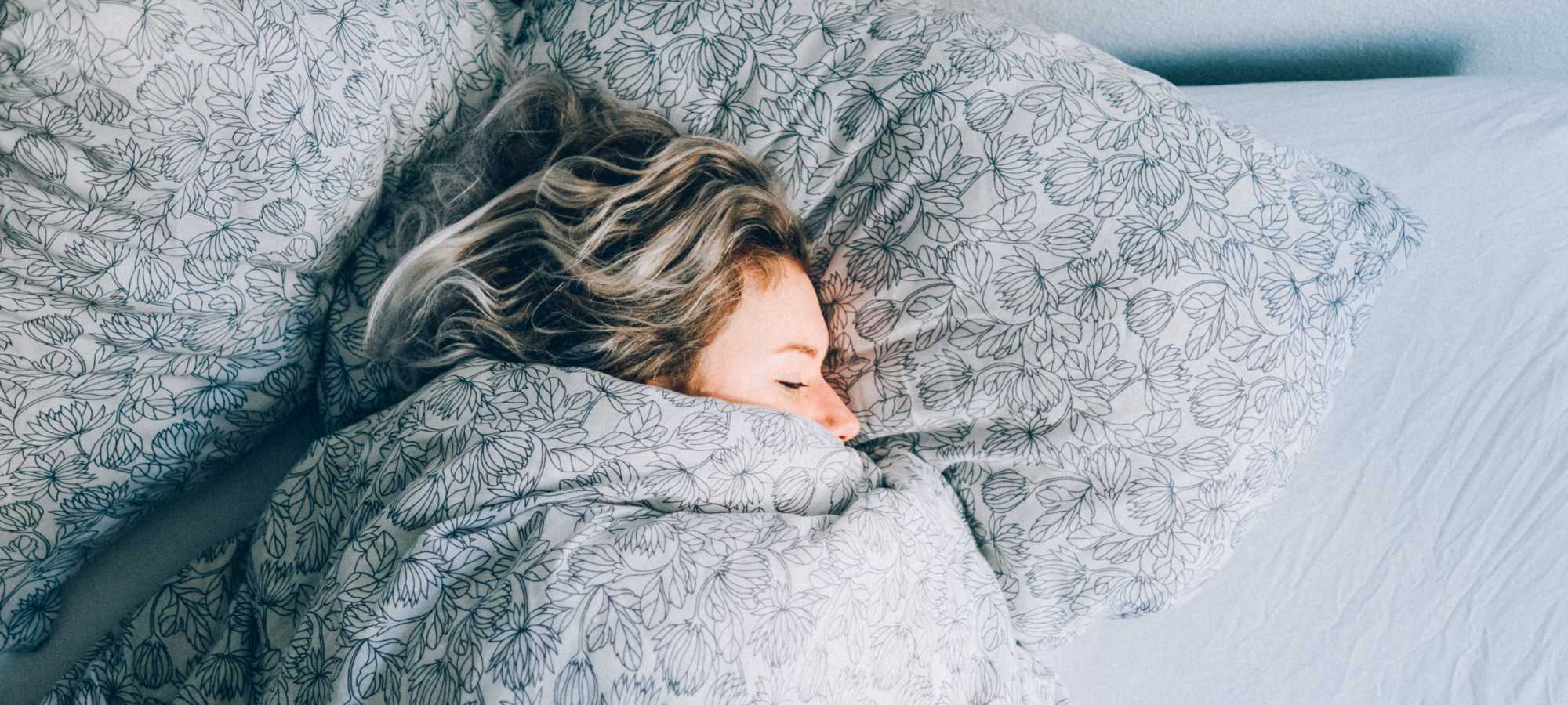 Blonde haired woman cozy under blankets