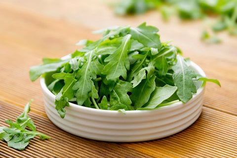 White bowl of baby arugula