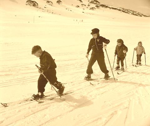Group of kids skiing on vintage skis.
