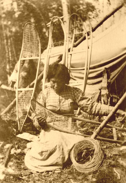 Native American woman weaving snowshoes.