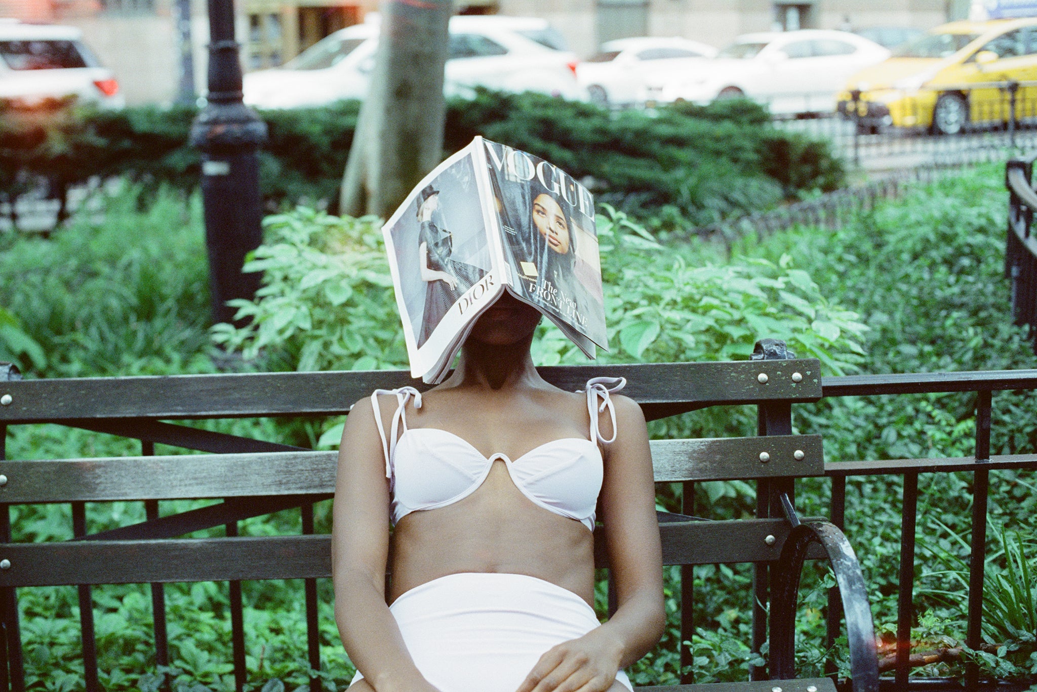 woman sitting on bench with a book on her face