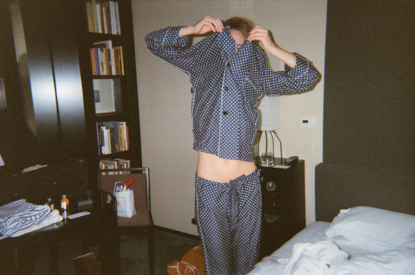 Woman wearing blue and white polka dot pajamas in a bedroom.