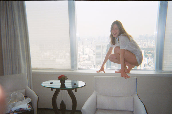 Woman in a white pajama shirt and shorts on a window sill.