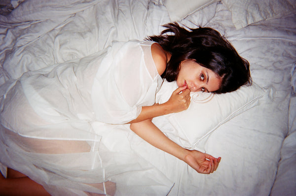 Woman in a white coverup laying on a bed