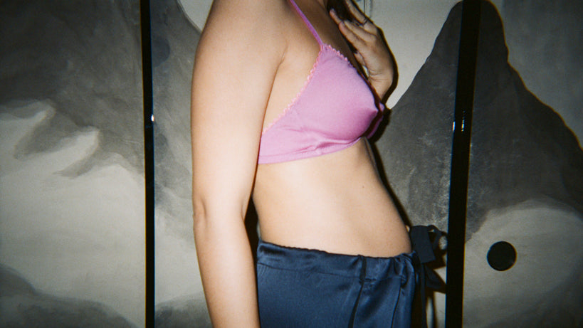 Side view of a woman in a pink bra and blue shorts