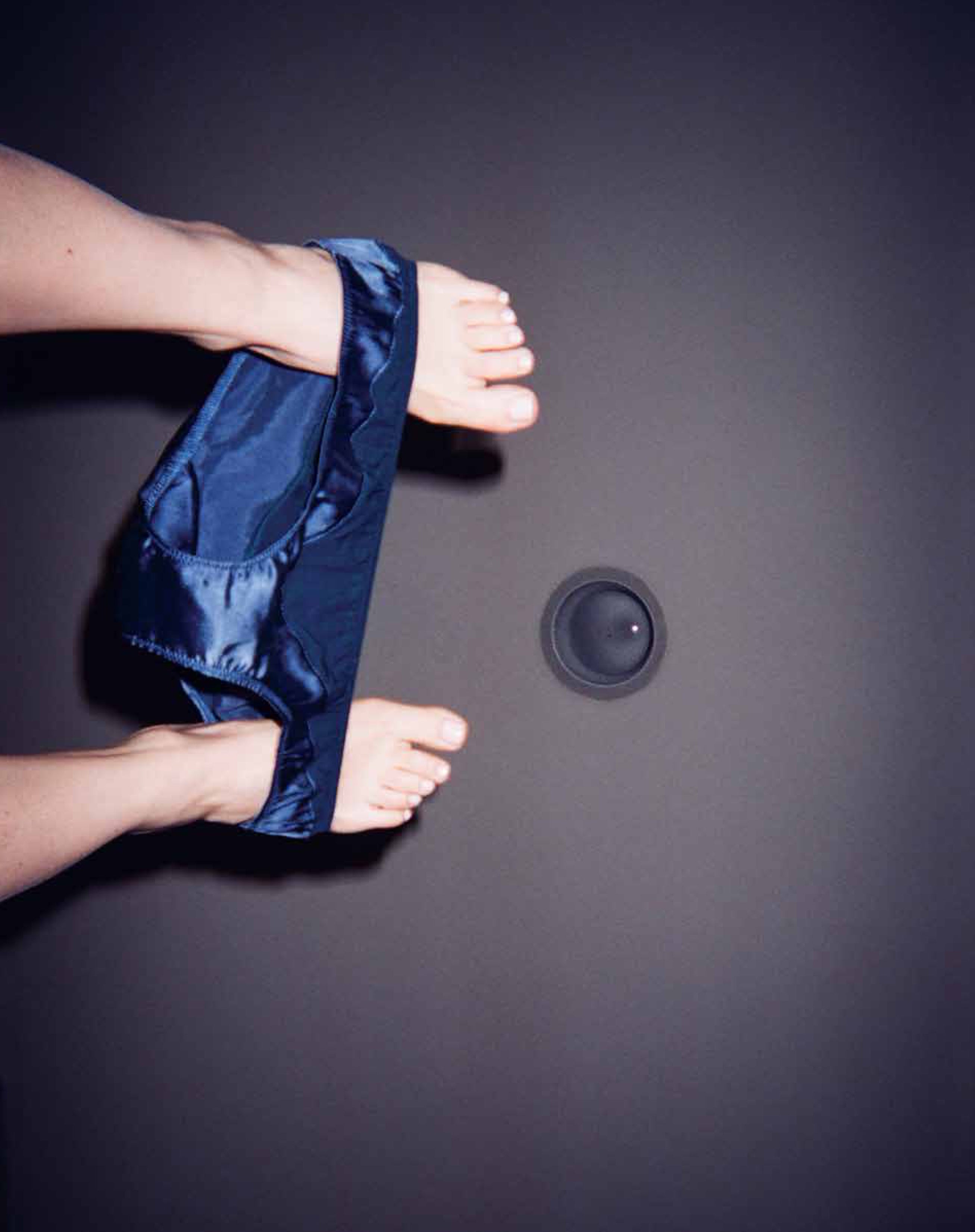 Women's feet holding blue underwear