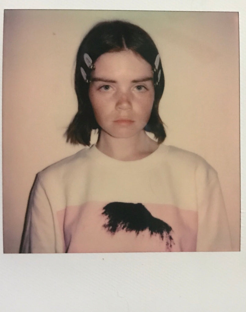 Polaroid photo of a woman in a white sweatshirt.