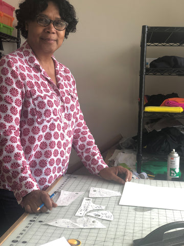 Woman standing at table making bra patterns.