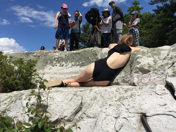 Photographers setting up a photo shoot of a woman in a black swimsuit.