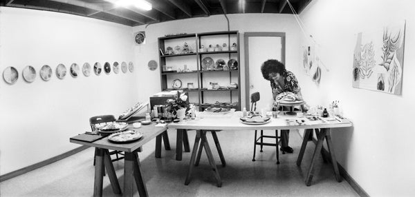 Black and white photo of a woman painting in an art studio.