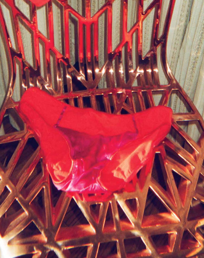 Red underwear laid on a gold chair.