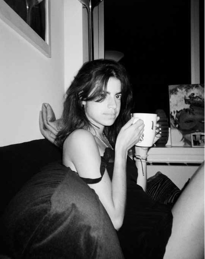 Black and white photo of a woman sipping on a mug in a black slip.
