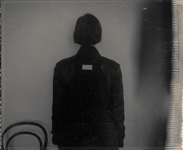 Black and white photo of a women's back in a black coat.