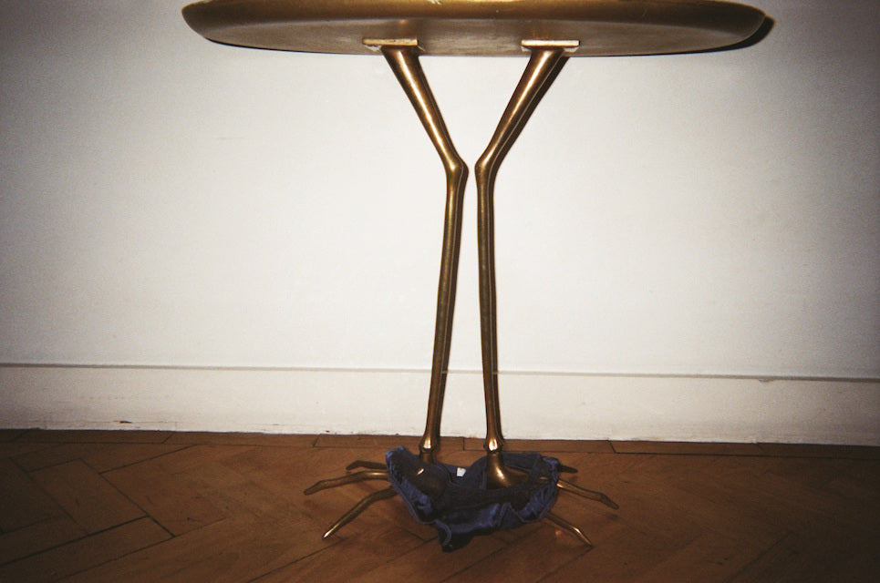 A gold table with blue underwear on it's legs.