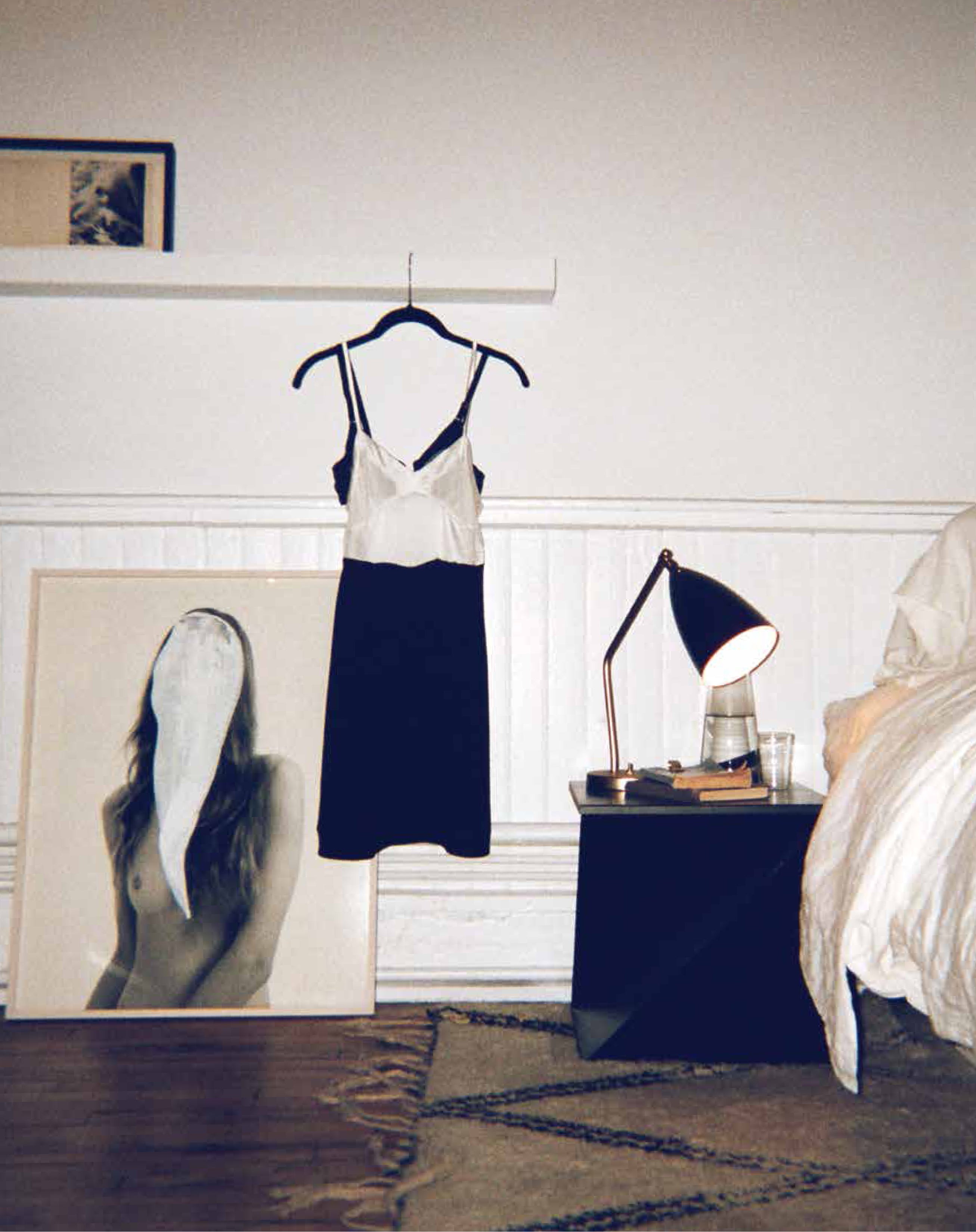 White and black chemise hung in a room with a desk and a photo of a woman.