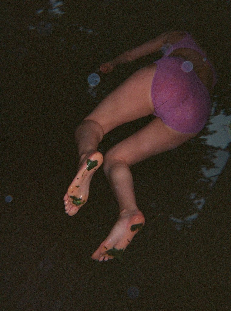 Woman in purple underwear bent over with mud on her feet.
