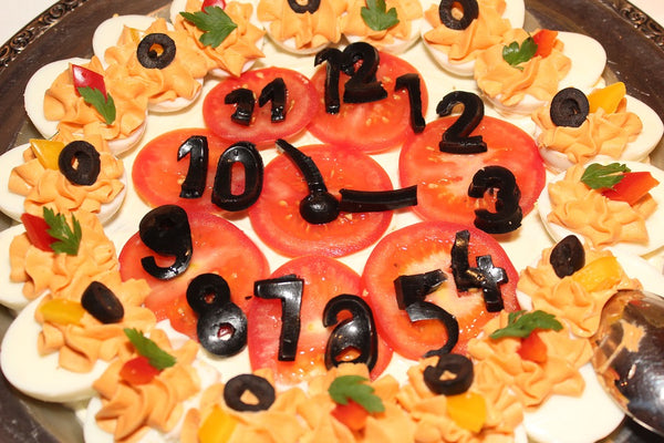 Concept: Food clock made of tomatoes, olives, deviled eggs