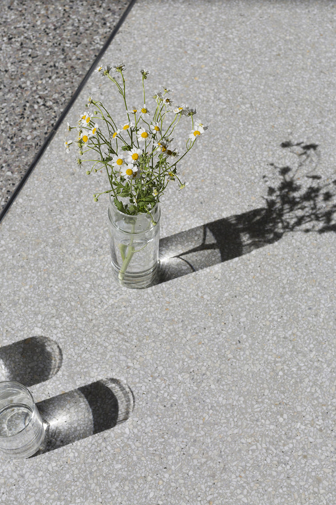 Water carafe used as a vase with daisies.