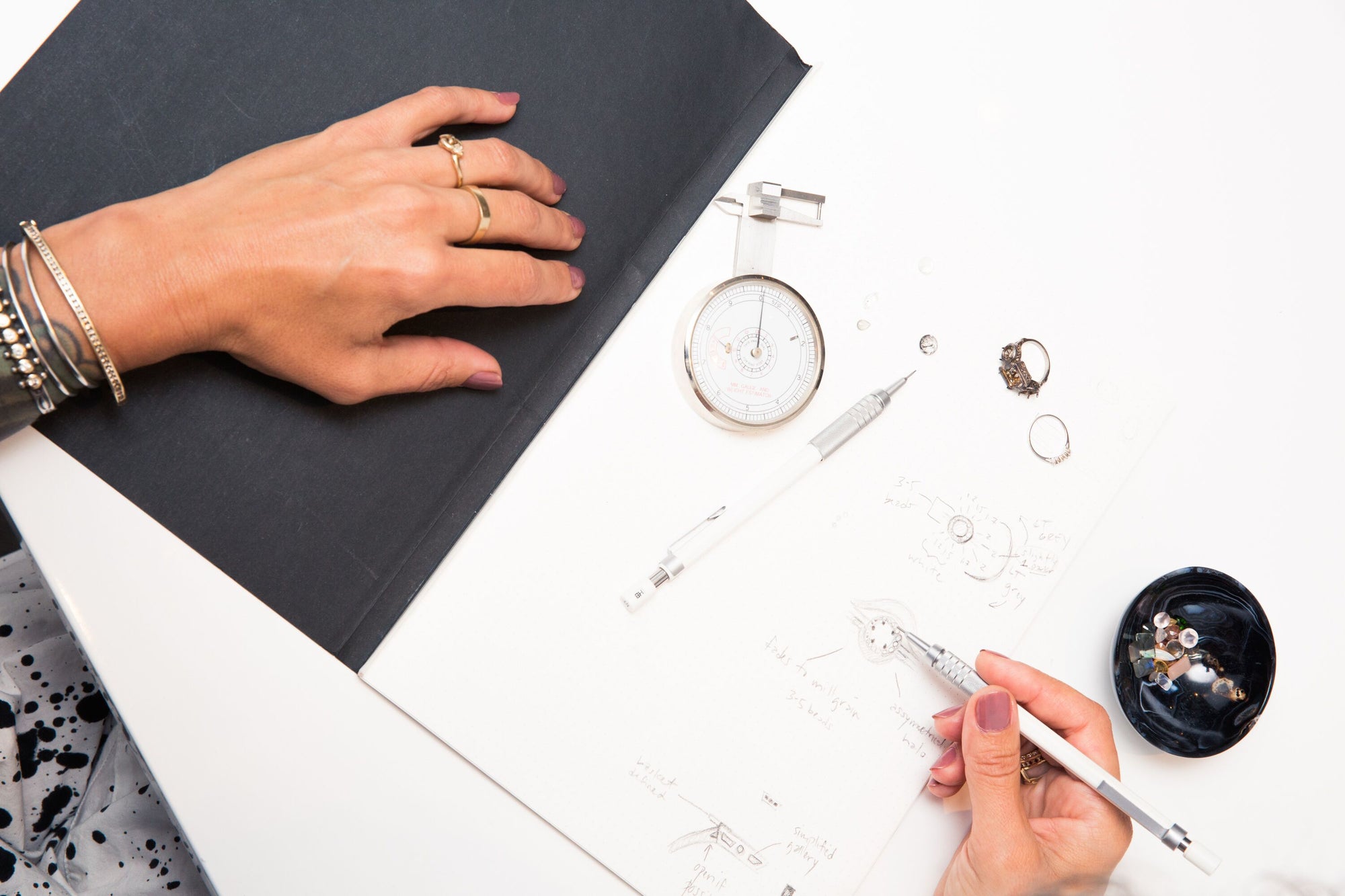 A bright bird's eye photo of a pair of hands sketching engagement rings and wedding bands.