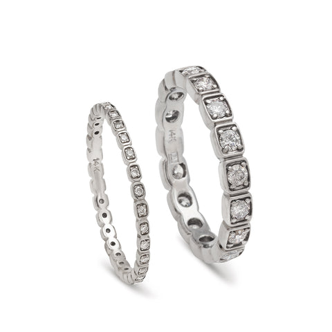 A tiny white diamond eternity band set in white gold next to a 3mm white diamond eternity band set in white gold.