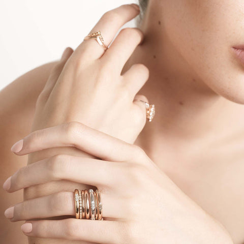 Three straight band with 5 clusters white diamond band set in yellow gold on a light-complextion models ring finger. 4