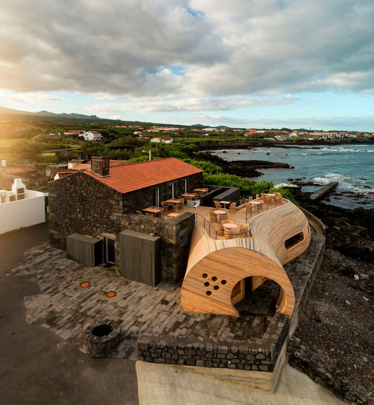 Cella Bar, ubicado en Madalena, Portugal, es el resultado de la renovación y ampliación de un espacio que había sido dejado por muchos años. La parte agregada se puede distinguir fácilmente ya que cuenta con un patrón orgánico que contrasta con el clásico edificio y, además, la madera se funde con la naturaleza de la zona. (Foto: FCC Arquitectos) 