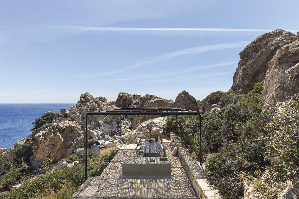 Through an open space, the house connects with a great outdoor terrace on the lowest area of the place, where another of the multiple views of the calm sea hides. In the picture below, the exposed concrete exterior of the property can be clearly seen, contrasting with the soft and light interior.