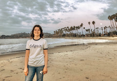 woman on beach wearing a California looks good on me tshirt