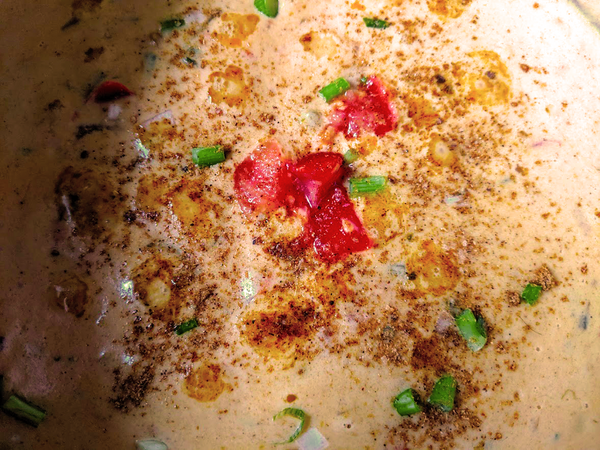 Queso with some chives, tomato and green onion garnish.