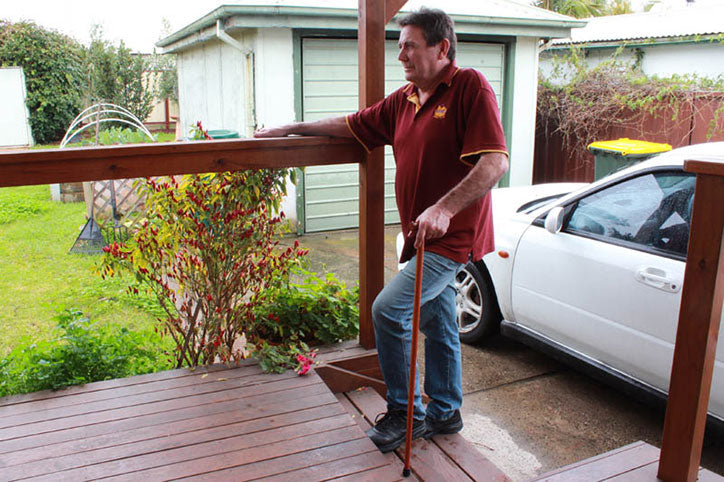 Photo of Greg using a walking stick to climb the stairs