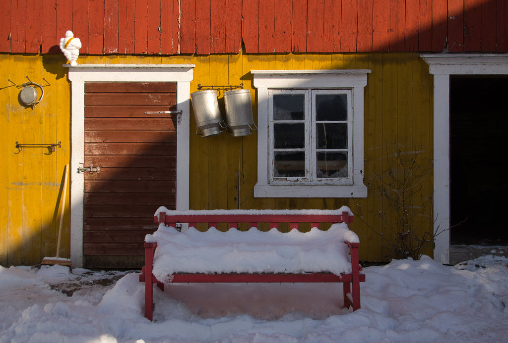 Snow-covered bench by the barn