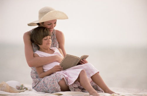 Mother and daughter reading on the beach