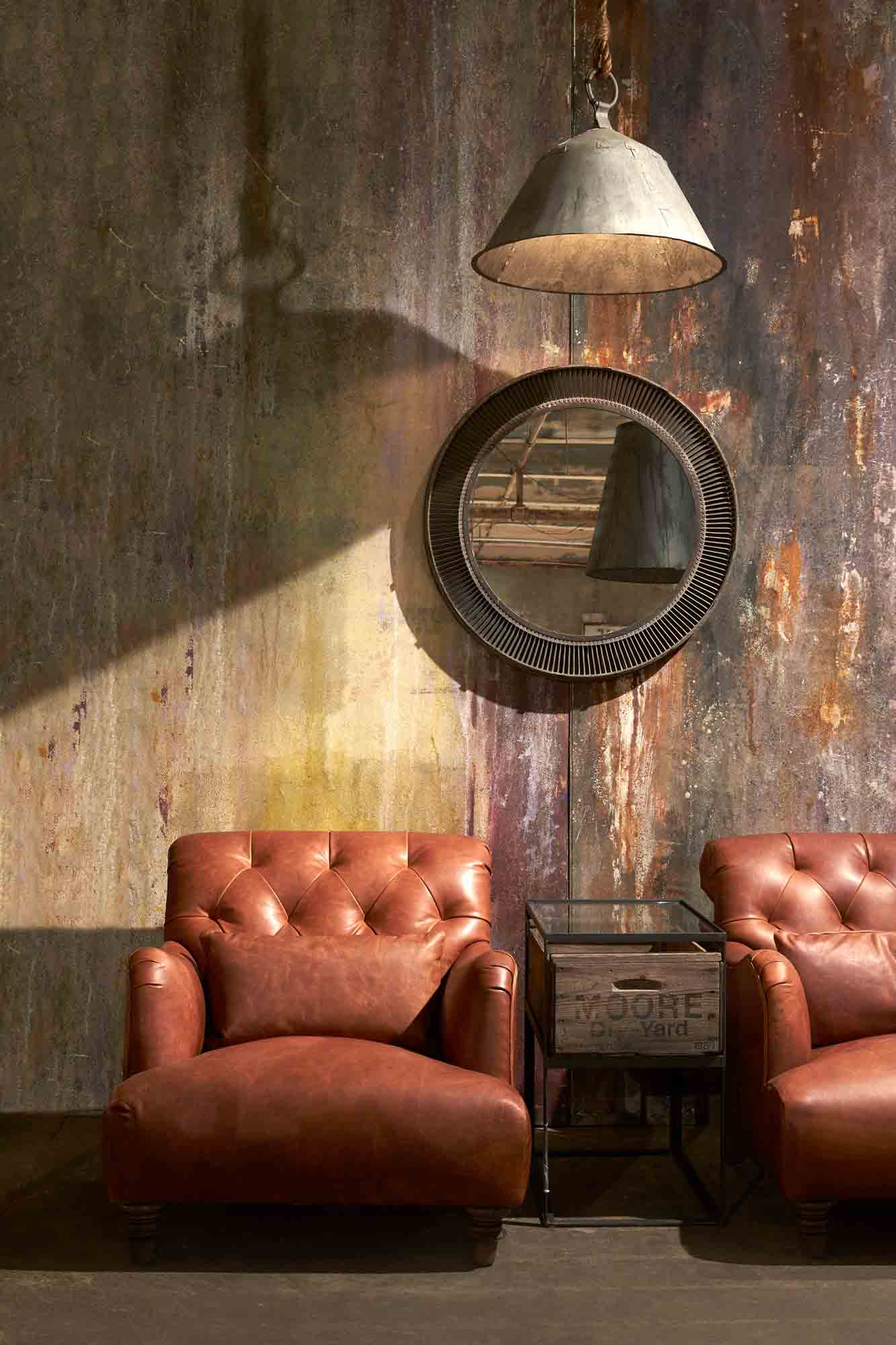  皮椅子在Spur Terracotta旁边的边桌. 坐在挂着灯和镜子的彩色墙壁前.  
